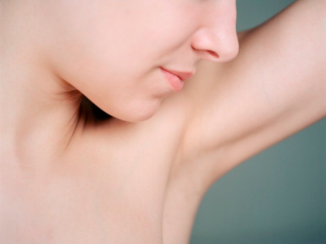 Young woman smelling armpit, close up